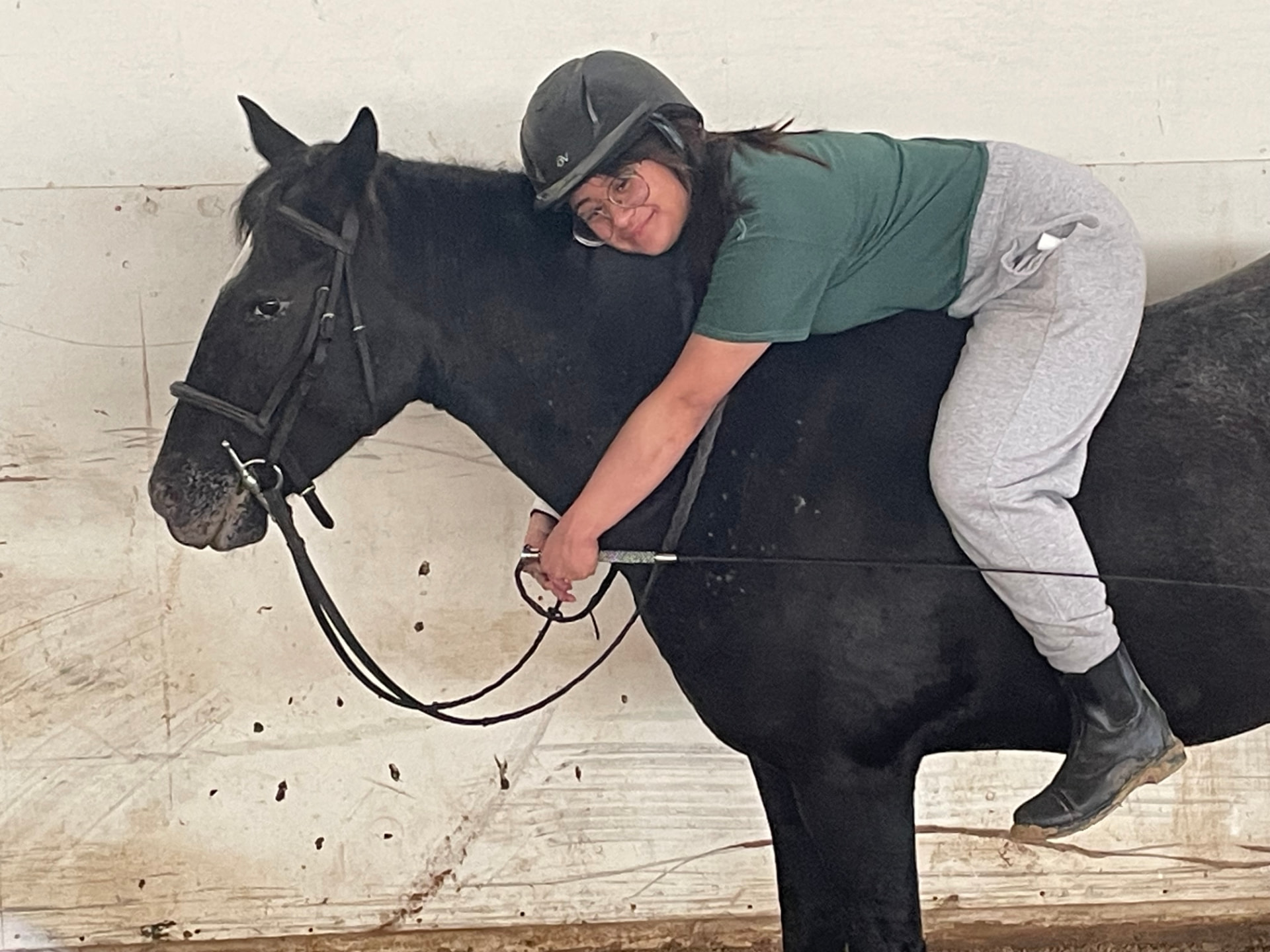 Rider leaning over a lesson horse in the barn